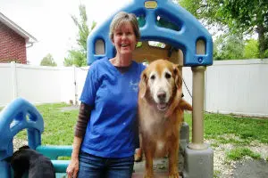 Woman smiling with golden retriever by playground.