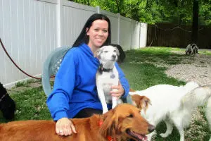 Woman with dogs in a fenced yard.